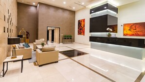 Eine moderne Lobby mit einer Rezeption, Sofas, einem Couchtisch und einer dekorativen Lampe.