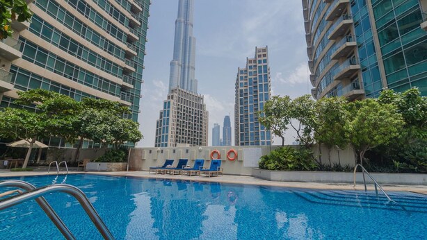 Ein Pool mit Liegestühlen und Blick auf hohe Gebäude, darunter ein markanter Wolkenkratzer.