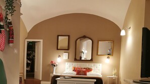Ein Wohnzimmer mit einer Couch, einem Couchtisch, einem Fernseher und einem Bett mit weißem Kopfteil.