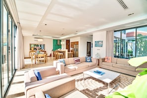 A spacious living room with a large sofa, a coffee table, and a dining area with a table and chairs.