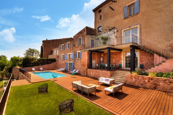 A large house with a swimming pool, outdoor furniture, and a well-maintained lawn.