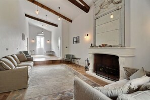A spacious living room with a fireplace, a large mirror, and a cozy seating area.