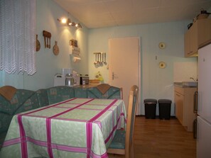 A compact kitchen with a dining table, chairs, and a refrigerator.