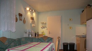 A compact kitchen with a dining table, chairs, and a refrigerator. - Bungalow Lange with 2 bedrooms - Bungalow Lange (Heringsdorf)