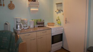 A compact kitchen with a coffee maker, toaster, and oven. There is a sink, a countertop, and a door with a handle. - Bungalow Lange with 2 bedrooms - Bungalow Lange (Heringsdorf)