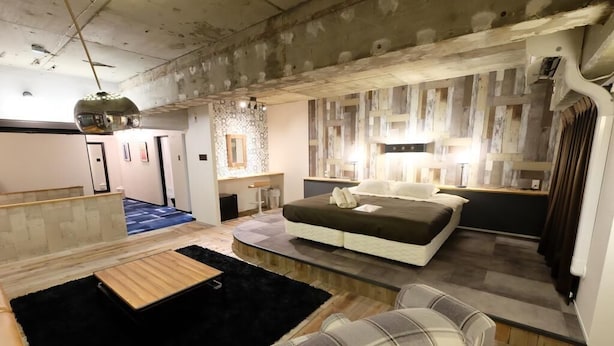 A bedroom with a bed, a nightstand, a dresser, and a large window. - Apartment with terrace (大阪市)