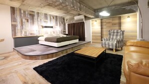 A modern bedroom with a bed, a chair, a sofa, a small table, and a black rug. - Apartment with terrace (大阪市)