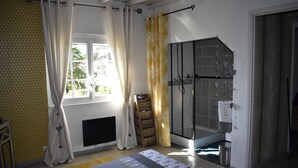 Une salle de bain avec une douche à parois de verre, une fenêtre avec des rideaux et un porte-serviettes.