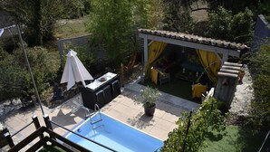 Un jardin avec une piscine, un espace salon extérieur et une terrasse couverte.