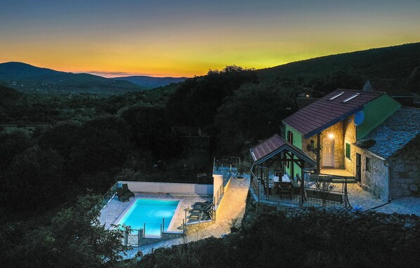 Escape to a secluded villa surrounded by lush mountains, featuring a pool and lounge chairs.