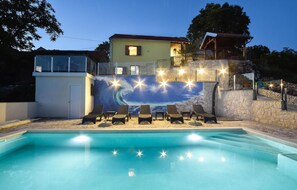 Relax by the pool surrounded by lounge chairs and a vibrant mural.
