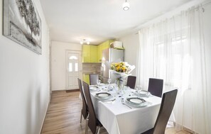 Enjoy meals in this dining area with a table for four, a kitchen, and a light fixture above.