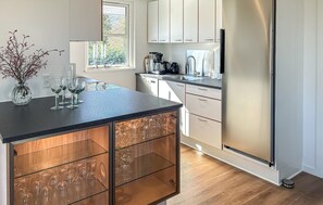 Una cocina moderna con una isla central, electrodomésticos de acero inoxidable y un ventanal con luz natural.