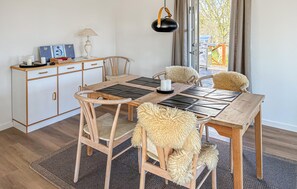 Un coin repas comprenant une table en bois, des chaises, un buffet et une lampe suspendue.