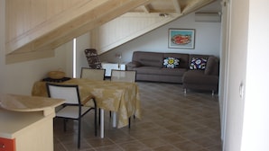 A dining area with a table and chairs, a sofa, and a painting on the wall. - Villa Fede (Zupa dubrovacka)