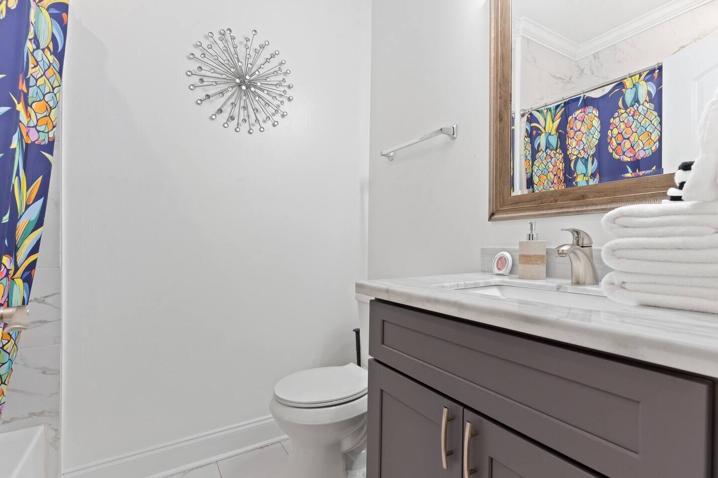 A bathroom with a white toilet, a sink with a mirror, and a shower curtain with a pineapple pattern.