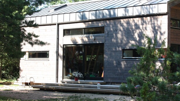 Una casa moderna con un gran ventanal y fachada de madera.