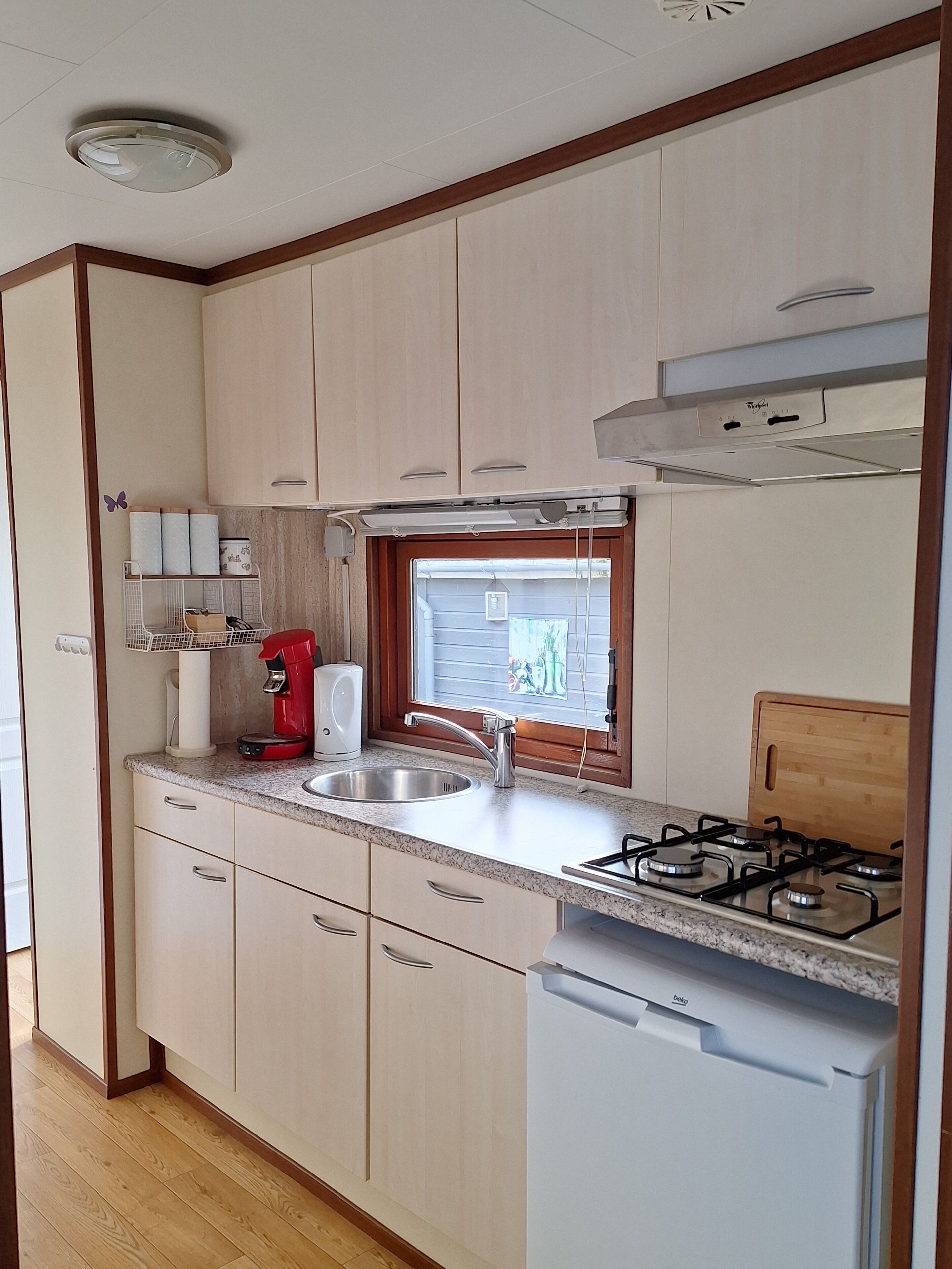 Une cuisine de taille réduite, équipée d’un évier, d’une cuisinière et de meubles de rangement en bois.