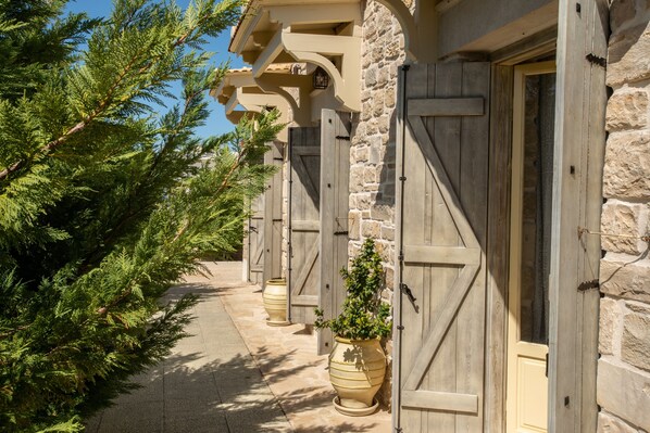 A stone building with wooden doors and a pathway lined with potted plants.