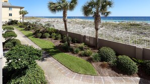 A beachfront property with a paved walkway, palm trees, and a view of the ocean. - Island Princess 204-Updated Beachfront with FAST Internet-Free Beach Service (Fort Walton Beach)