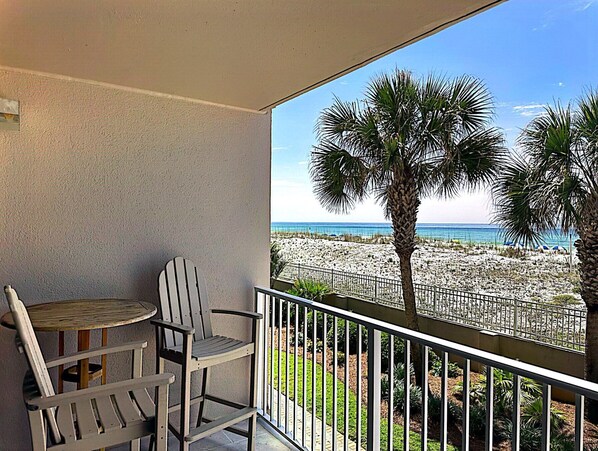 A balcony with a view of the beach, a table, and two chairs. - Island Princess 204-Updated Beachfront with FAST Internet-Free Beach Service (Fort Walton Beach)