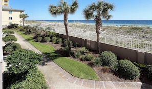 A beachfront property with a paved walkway, palm trees, and a view of the ocean. - Island Princess 204-Updated Beachfront with FAST Internet-Free Beach Service (Fort Walton Beach)