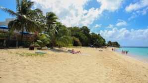 Ein Strand mit Palmen, sandigem Ufer und blauem Himmel.