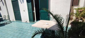 A patio with a table and chairs, green shutters, and potted plants. - Palazzo Ricordi (Ugento)
