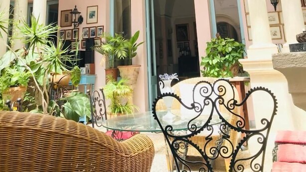 Un patio interior amplio con una zona de estar central, rodeado de columnas y plantas en macetas.