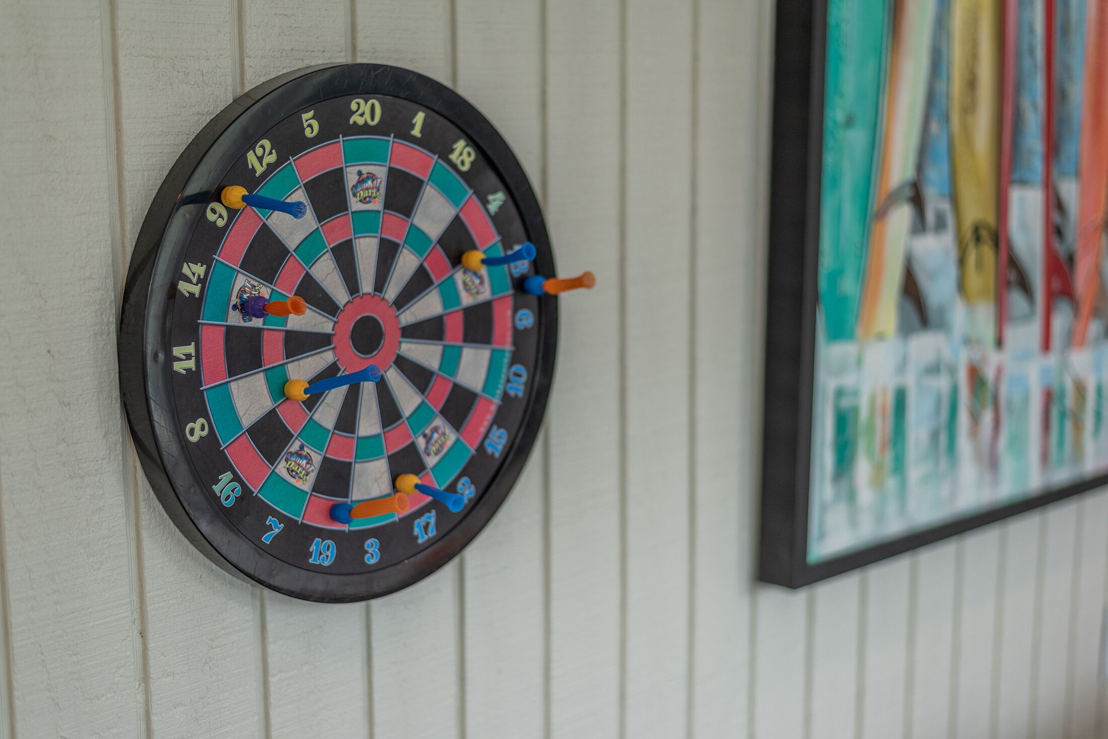 Une cible de fléchettes fixée au mur, avec un tableau encadré à sa droite.