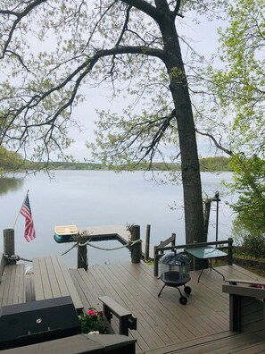 A wooden deck with a grill, a table, and a chair. - Charming cottage on quiet lake (Climax)