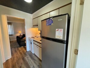 A compact kitchen with a stainless steel refrigerator, a stove, and a sink.