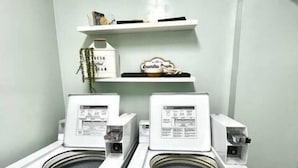 A laundry area with two front-loading washing machines and a shelf above them.