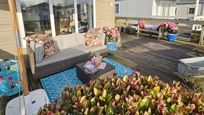 Un espace patio aménagé avec un canapé, une table agrémentée d’objets décoratifs et un grand parasol.