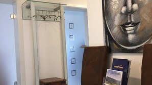 A modern interior with a glass shower enclosure, a brown leather sofa, a small wooden table, and a wall-mounted information stand. - City holiday apartment Müllheim (Müllheim)