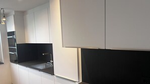 A modern kitchen with white cabinetry, a black countertop, and built-in appliances. - City holiday apartment Müllheim (Müllheim)