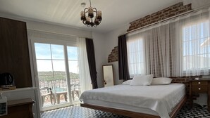 A hotel room with a large bed, a desk, and a view of the city. - Villa Veria (Cesme)