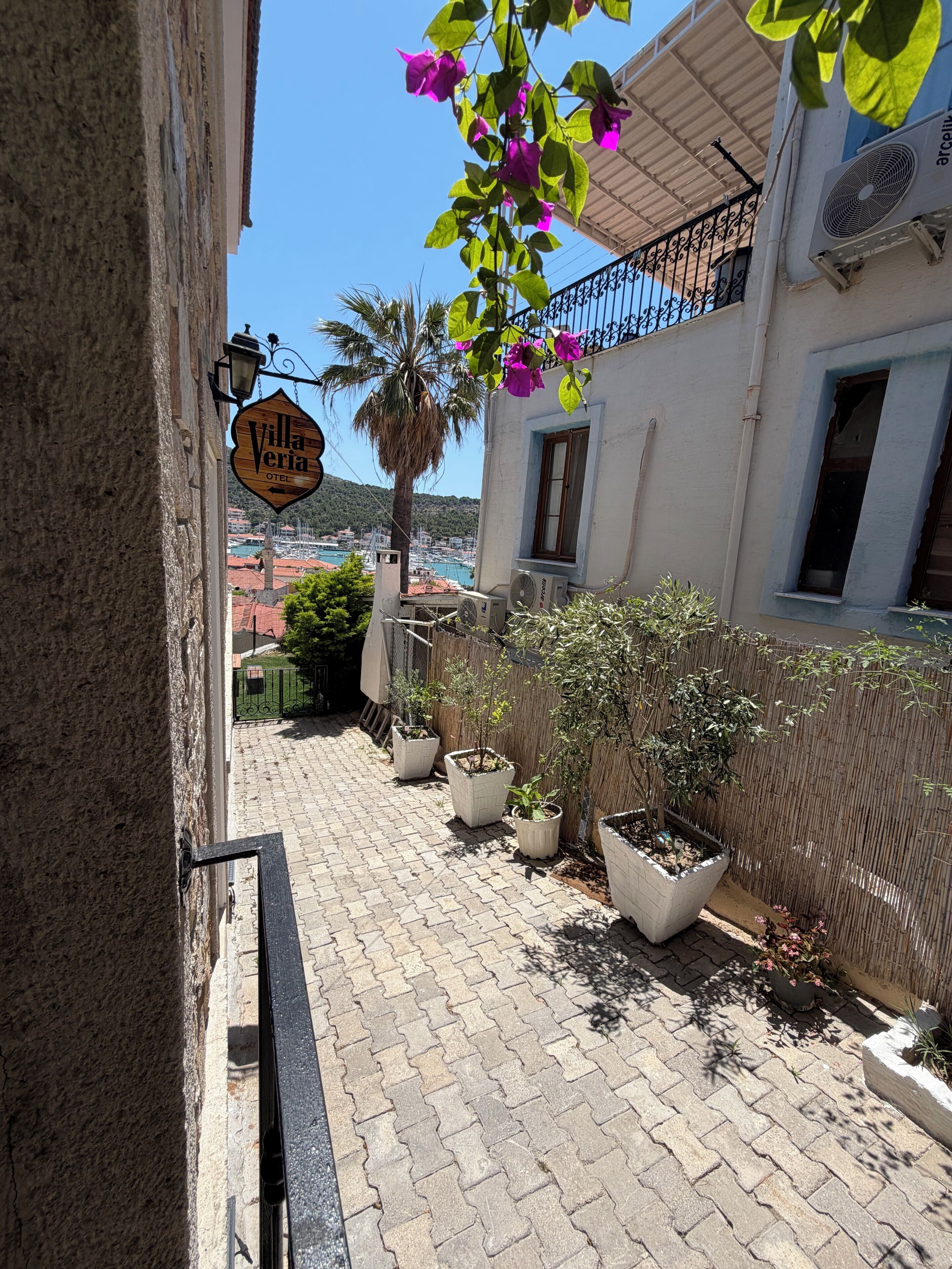 Un chemin pavé mène à un bâtiment sur lequel on peut lire une enseigne indiquant « Villa Veria Hotel ».