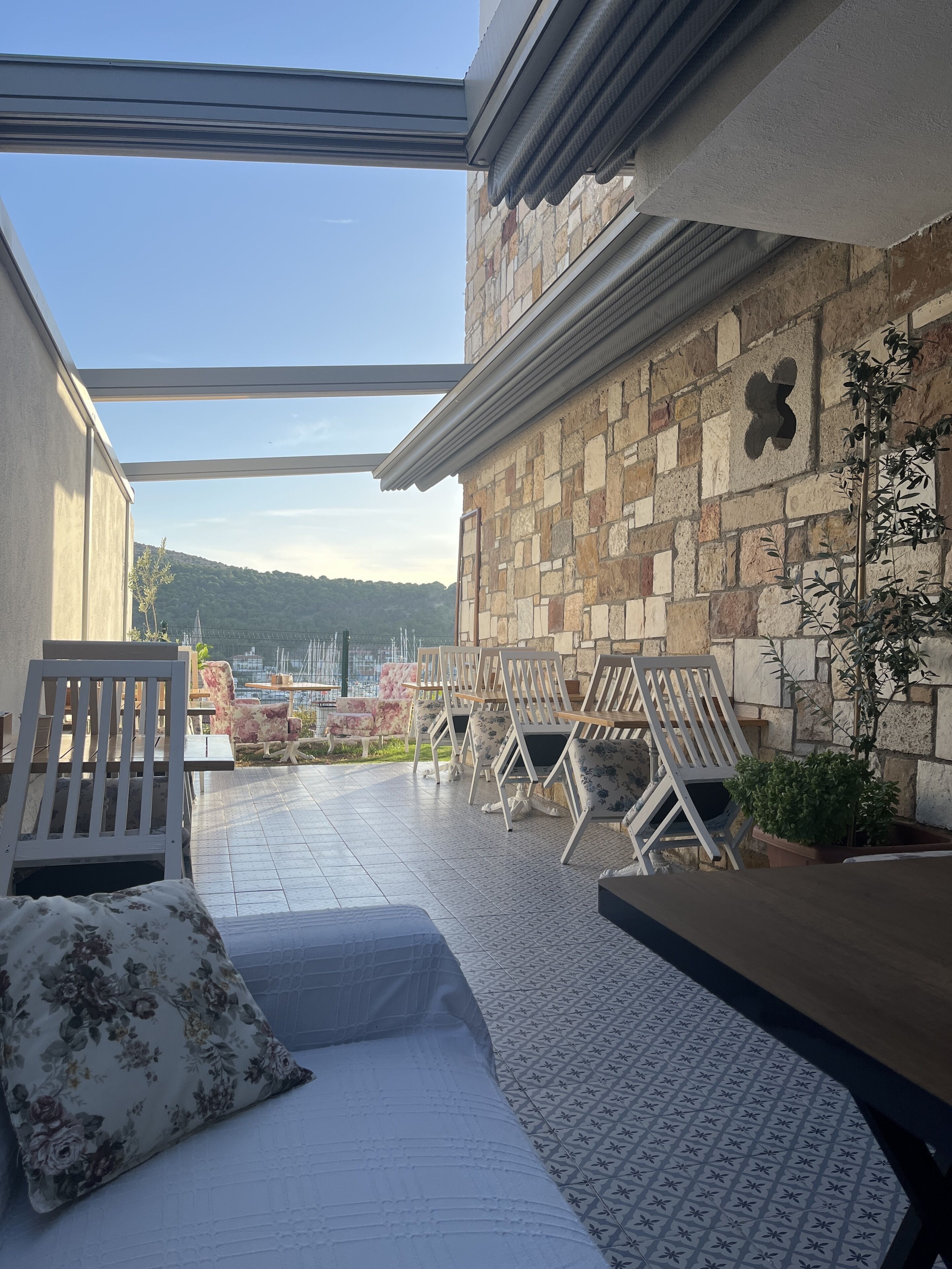 A rooftop terrace with stone walls, a view of the city, and outdoor furniture.