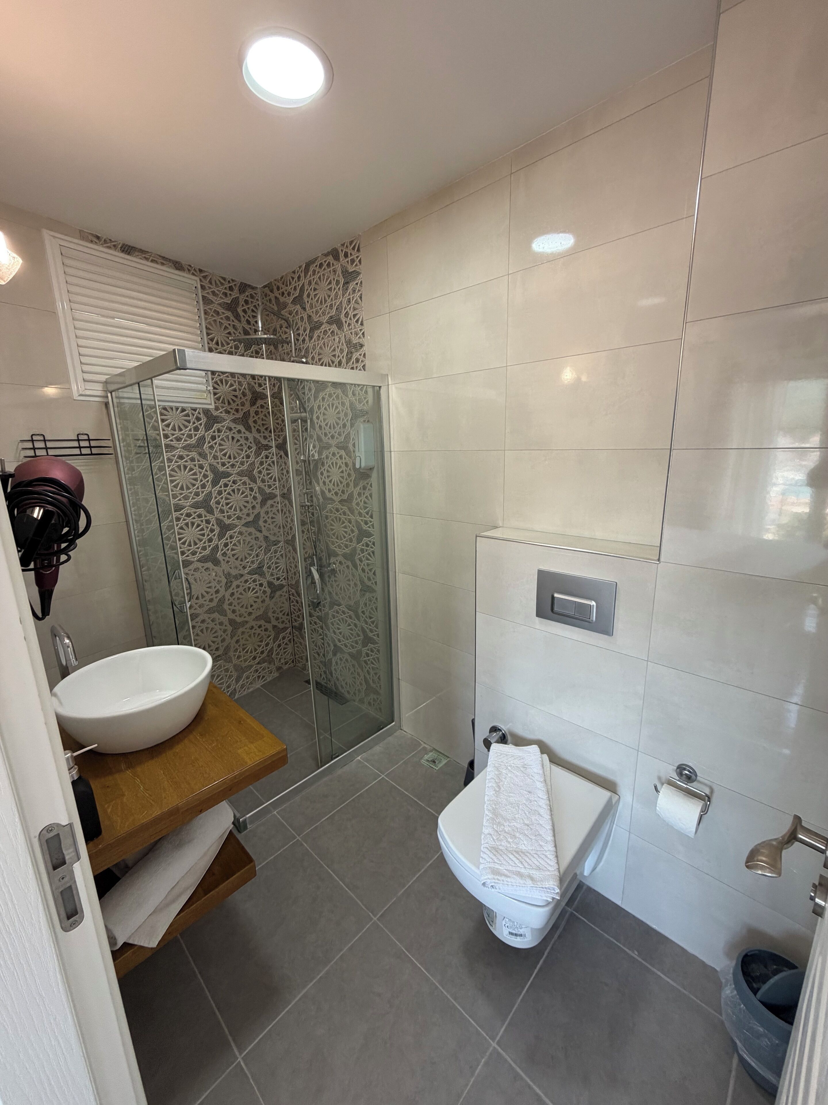Ein modernes Badezimmer mit einer gläsernen Duschkabine, einem weißen Waschbecken und einer Toilette.