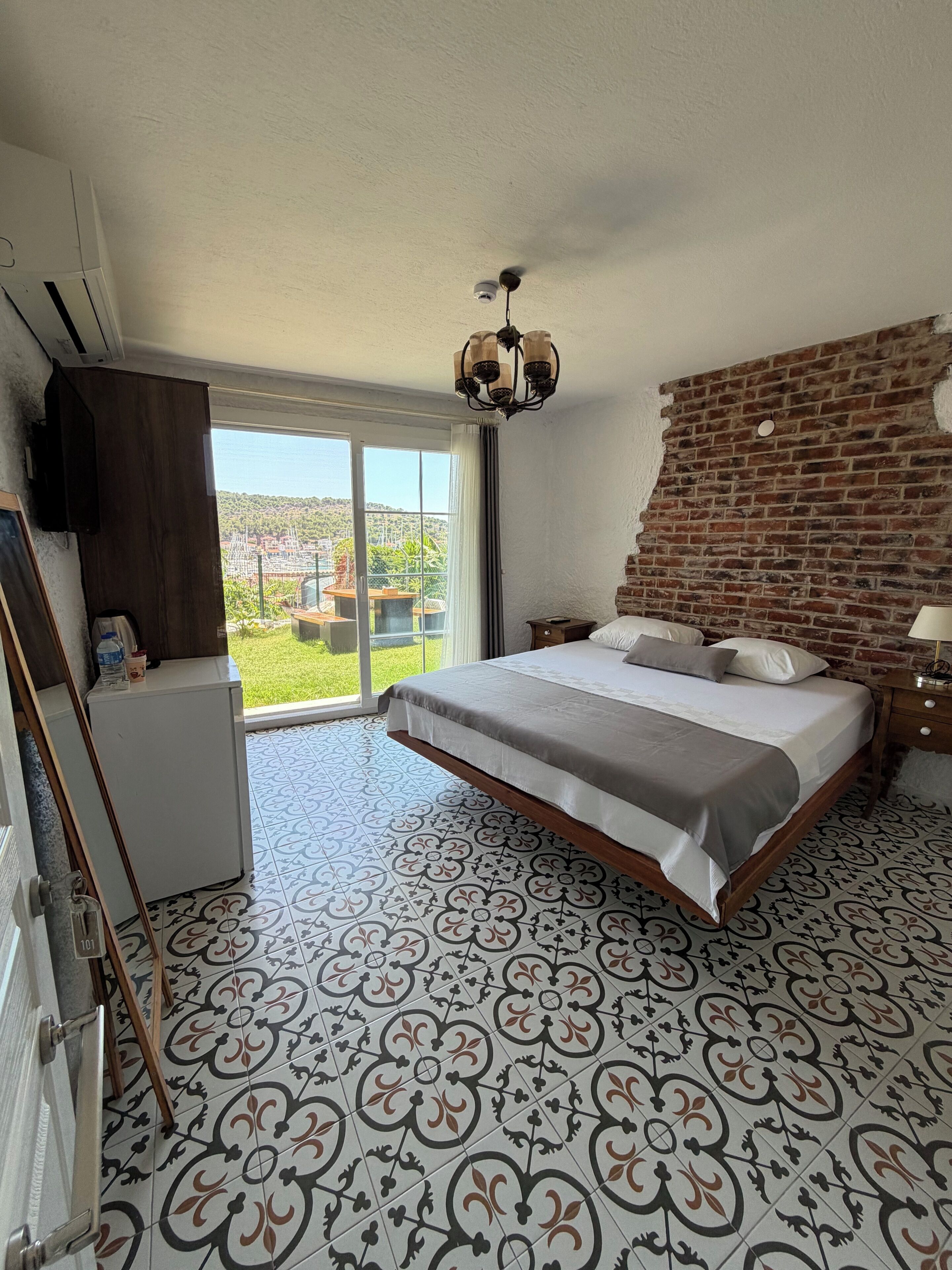 Un dormitorio con una cama grande, una pared de ladrillo y vistas a un paisaje verde.