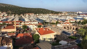 A marina with numerous boats, a town with red-roofed buildings, and a hill in the background. - Villa Veria (Cesme)