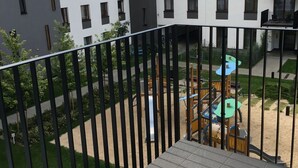 Un edificio residencial con varios balcones, un área de juegos y una entrada con portón.