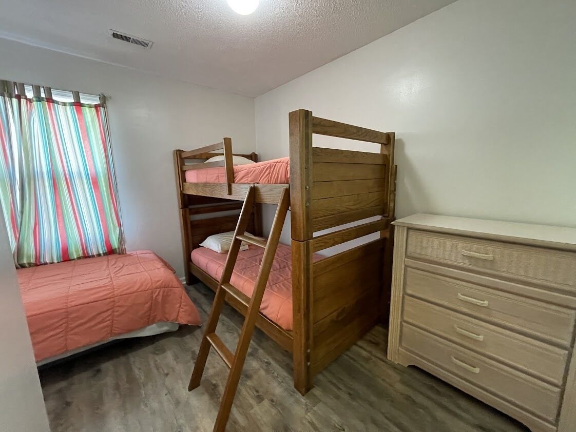 A room with bunk beds, a desk, and a dresser.