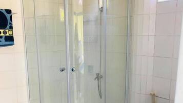 A corner shower enclosure with a glass door, a toilet, and a towel rack on the wall.
