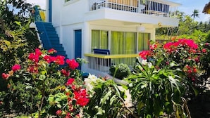 A two-story building with a balcony, surrounded by lush greenery and vibrant flowers. - Sweet Water Resort (Zamboanguita)
