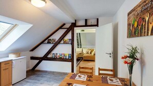 Uma cozinha acolhedora com uma escada de madeira, uma área de jantar com jogos americanos com tema de café e um quadro de utensílios de cozinha na parede.