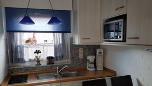 Une cuisine compacte équipée d’un évier, d’une machine à café et d’un four à micro-ondes.