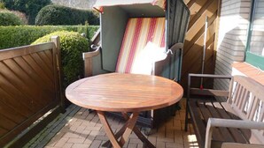 Un espace patio avec une table ronde en bois, une chaise à rayures et un banc.