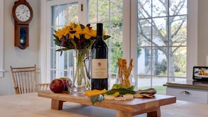 Een houten tafel met een fles wijn, een vaas met bloemen en diverse gerechten.